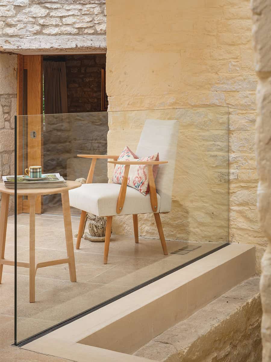 The Mount sheltered courtyard terrace with armchair behind frameless glass balustrade, Stroud cottage
